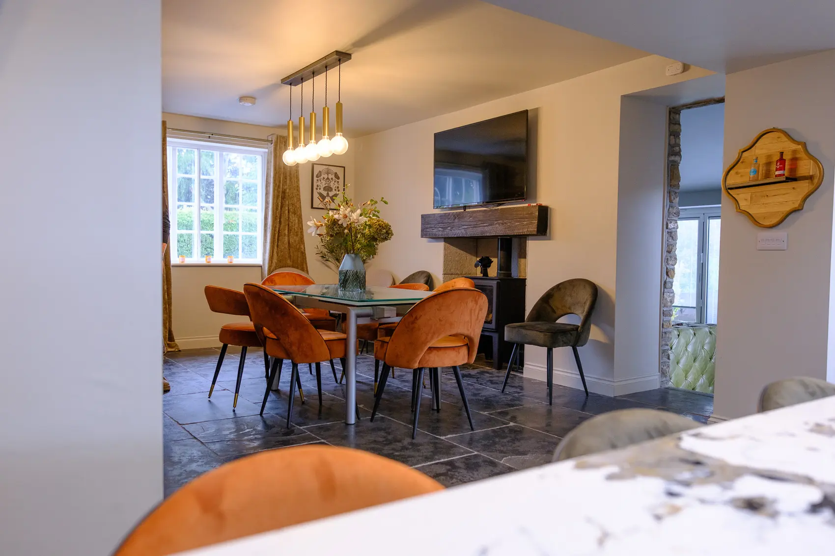 Dining space with exposed stone, an oak beam mantel and a log burner, renovated by Abbey Group